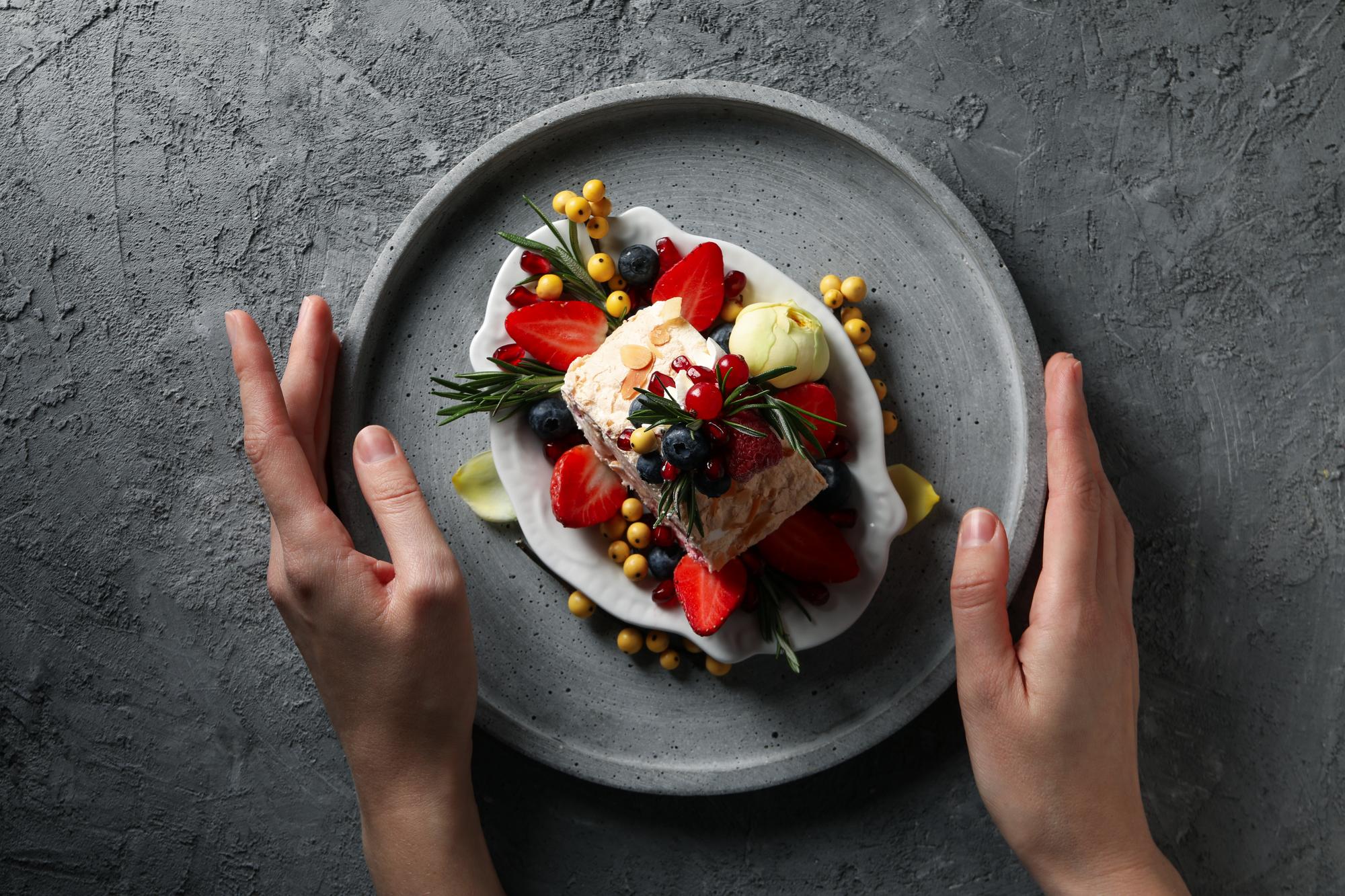 close-up of hands plating a composed dish